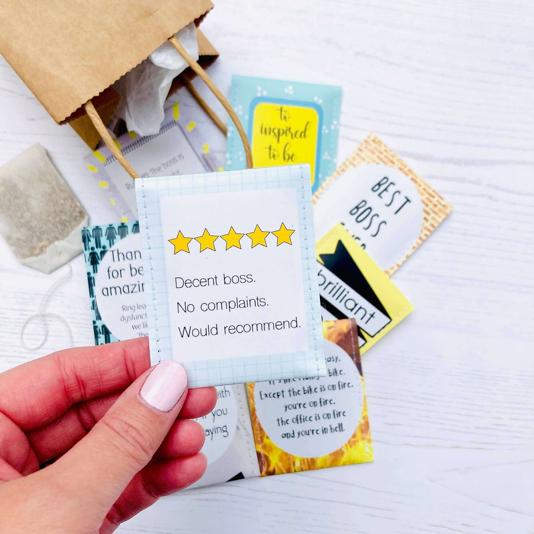 Hand holding a review card for Boss Tea Giftset featuring five stars and positive feedback.