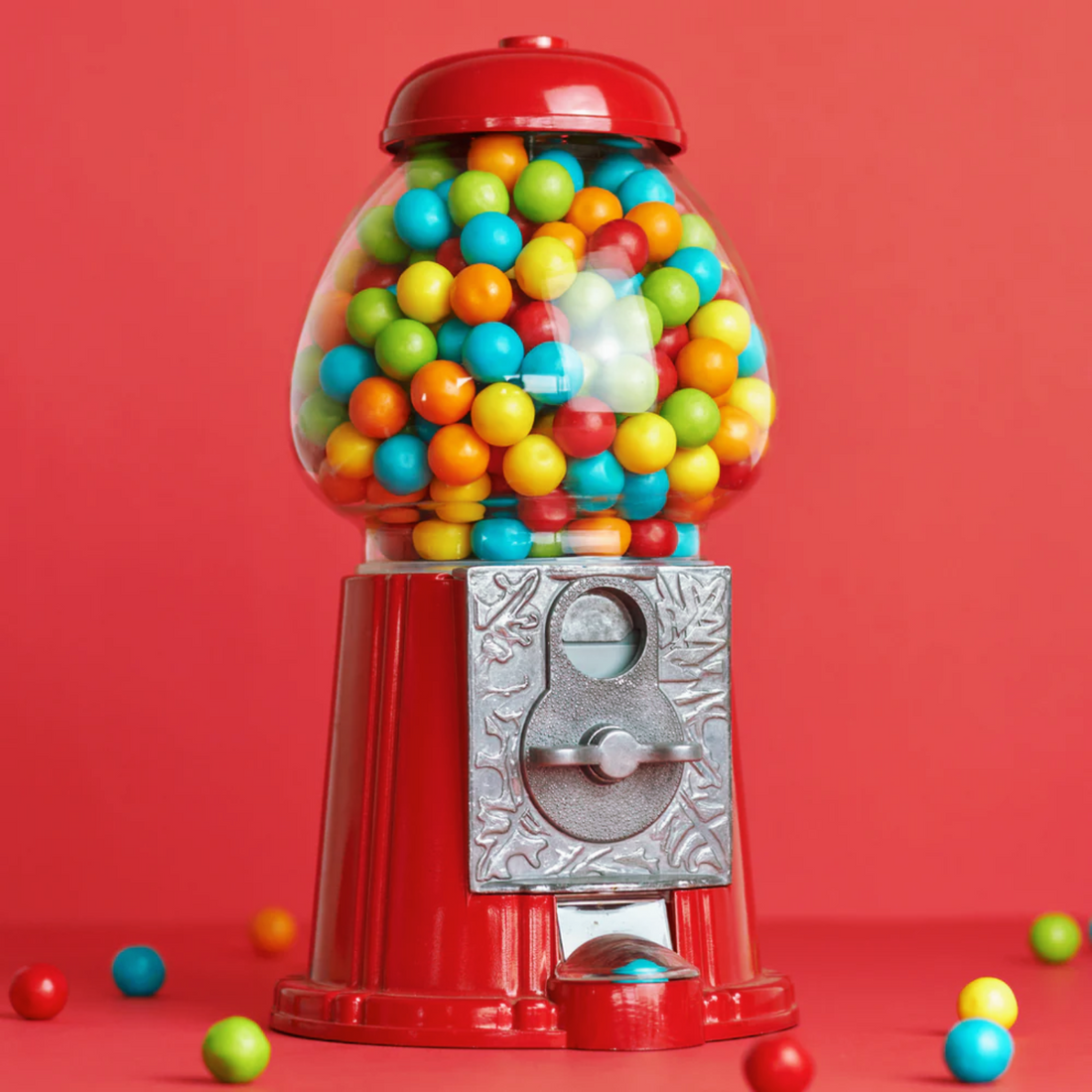 American Dream Gumball Machine filled with colorful gumballs against a bright red background.