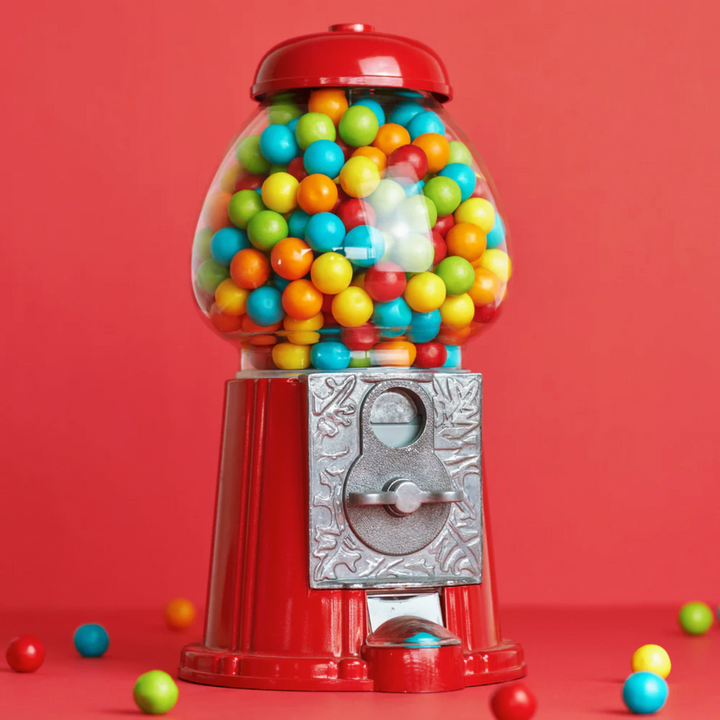 American Dream Gumball Machine filled with colorful gumballs against a bright red background.