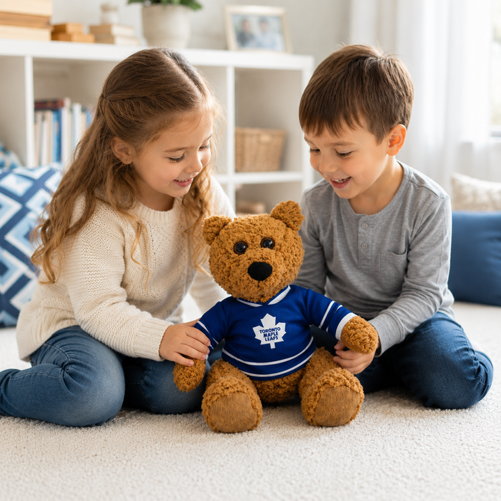 Two children holding a teddy bear wearing a sports jersey in a living room.