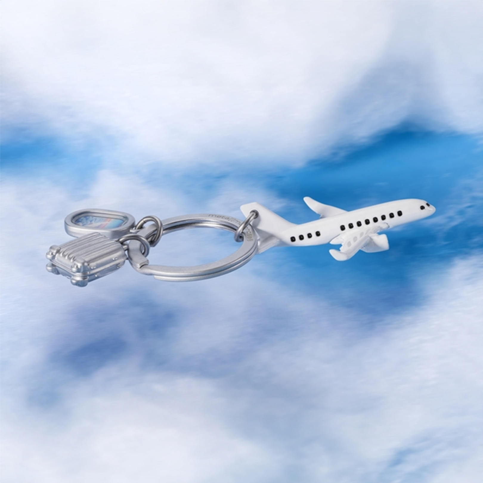 Airplane keychain with a suitcase charm against a cloudy sky background