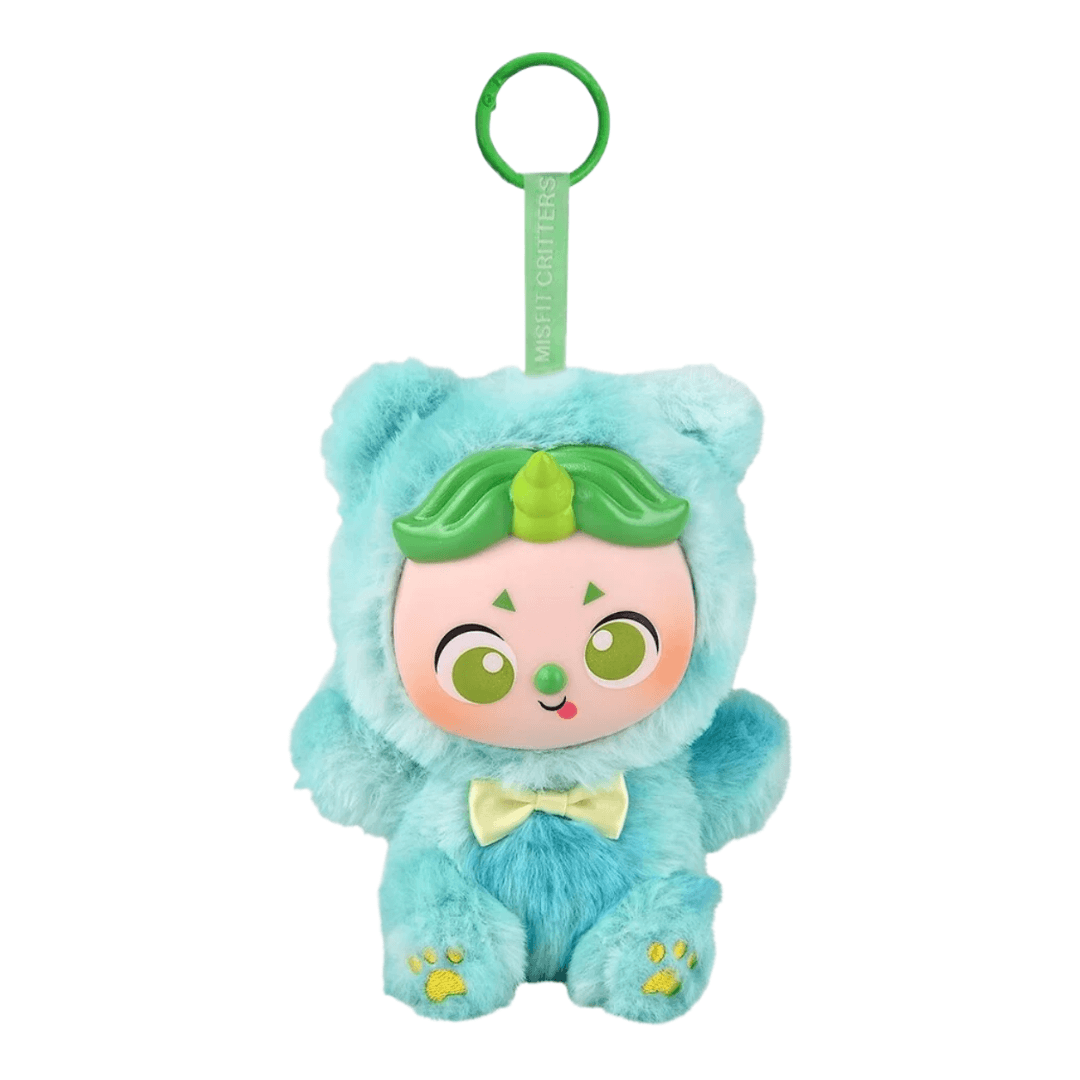 A cute, plush character keychain or bag charm featuring a light blue furry character dressed in a green leafy costume with a green ring at the top. The face has a pale pink skin tone with large green eyes, a green nose, and a small yellow bow tie.