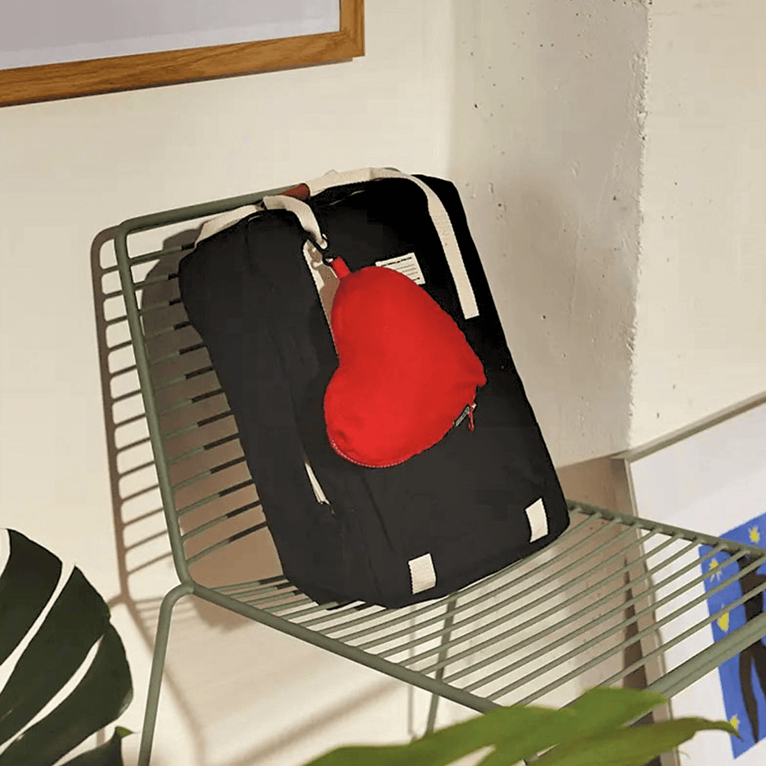 Nomad Heart Foldable Backpack resting on a chair, featuring a red heart-shaped pouch for added style and functionality.