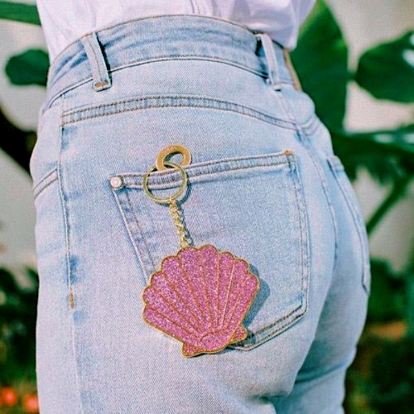 Oversized Shell Keychain attached to the back pocket of denim jeans, showcasing coastal-inspired design.