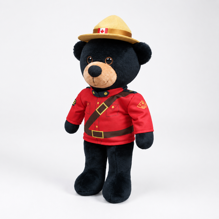 Plush bear wearing a red uniform and hat with a Canadian flag on a white background