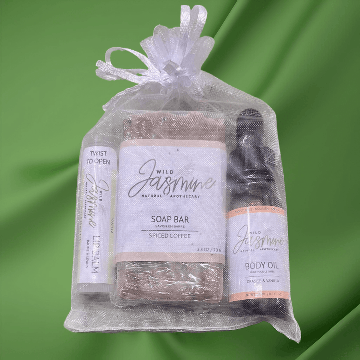 Set of Wild Jasmine soap bar, body oil, and other products in a clear bag on a green background