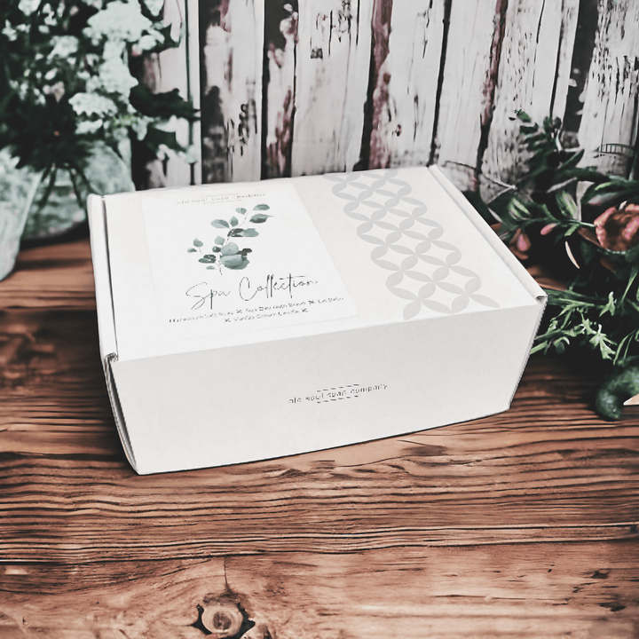 Handcrafted Canadian Spa Collection gift set box on wooden table, surrounded by greenery and flowers.