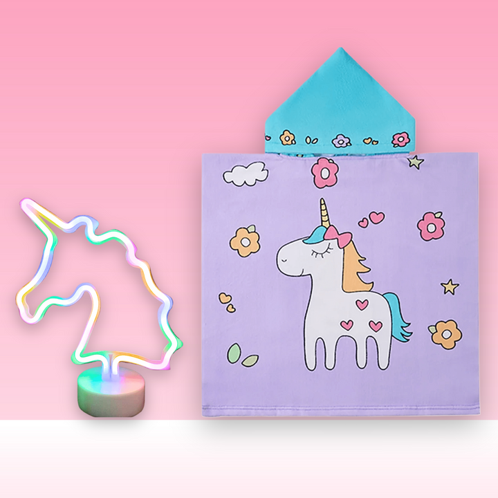 Children's hooded towel with unicorn design on a pink background, next to a colorful unicorn-shaped night light.