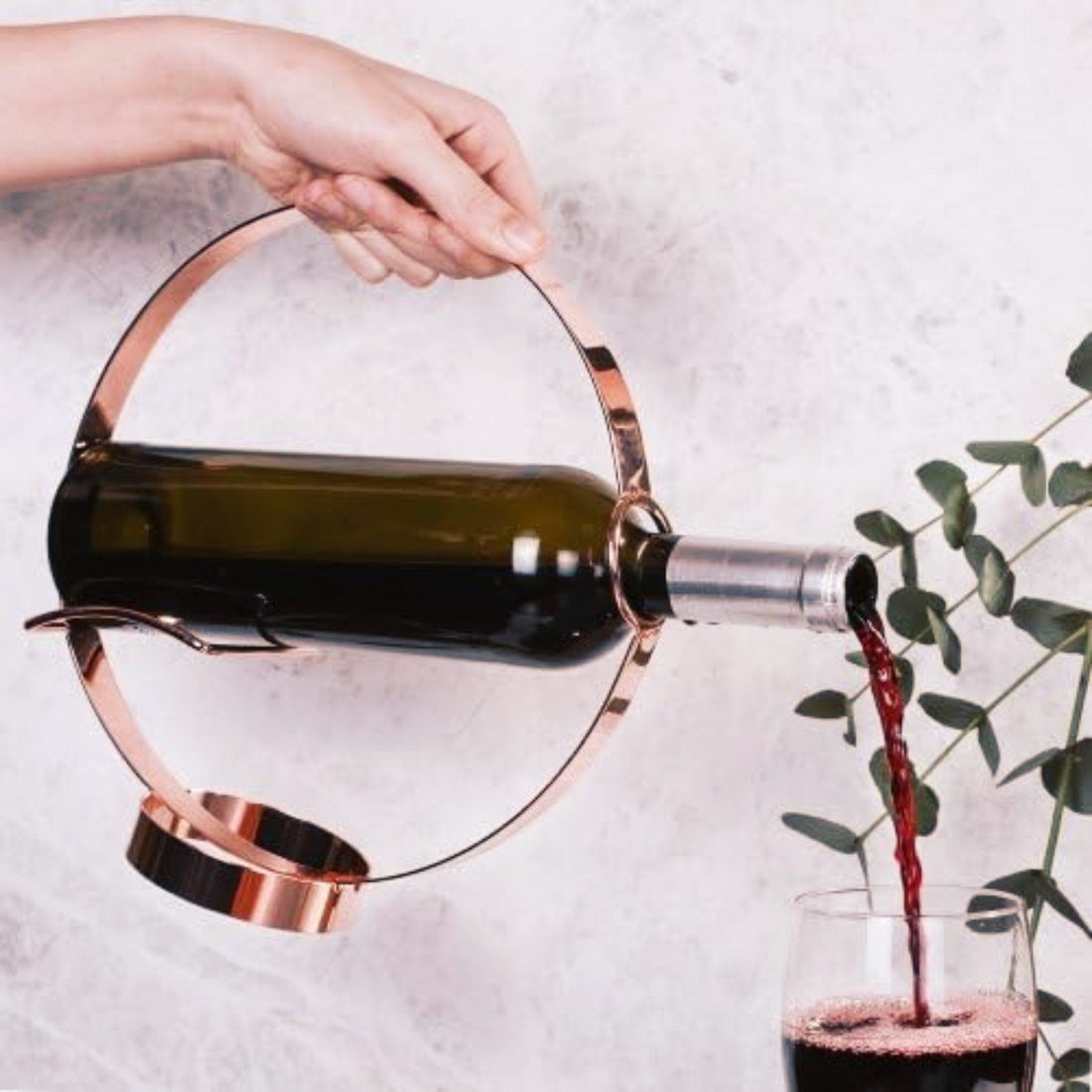 Elegant Wine Bottle Holder and Pourer showcasing a wine bottle being poured into a glass with a stylish metallic holder.