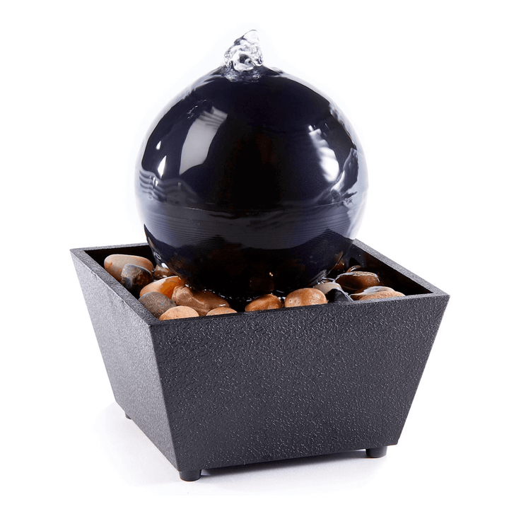 Ball table fountain with LED light, featuring a central ball and smooth water flow, set on decorative pebbles.