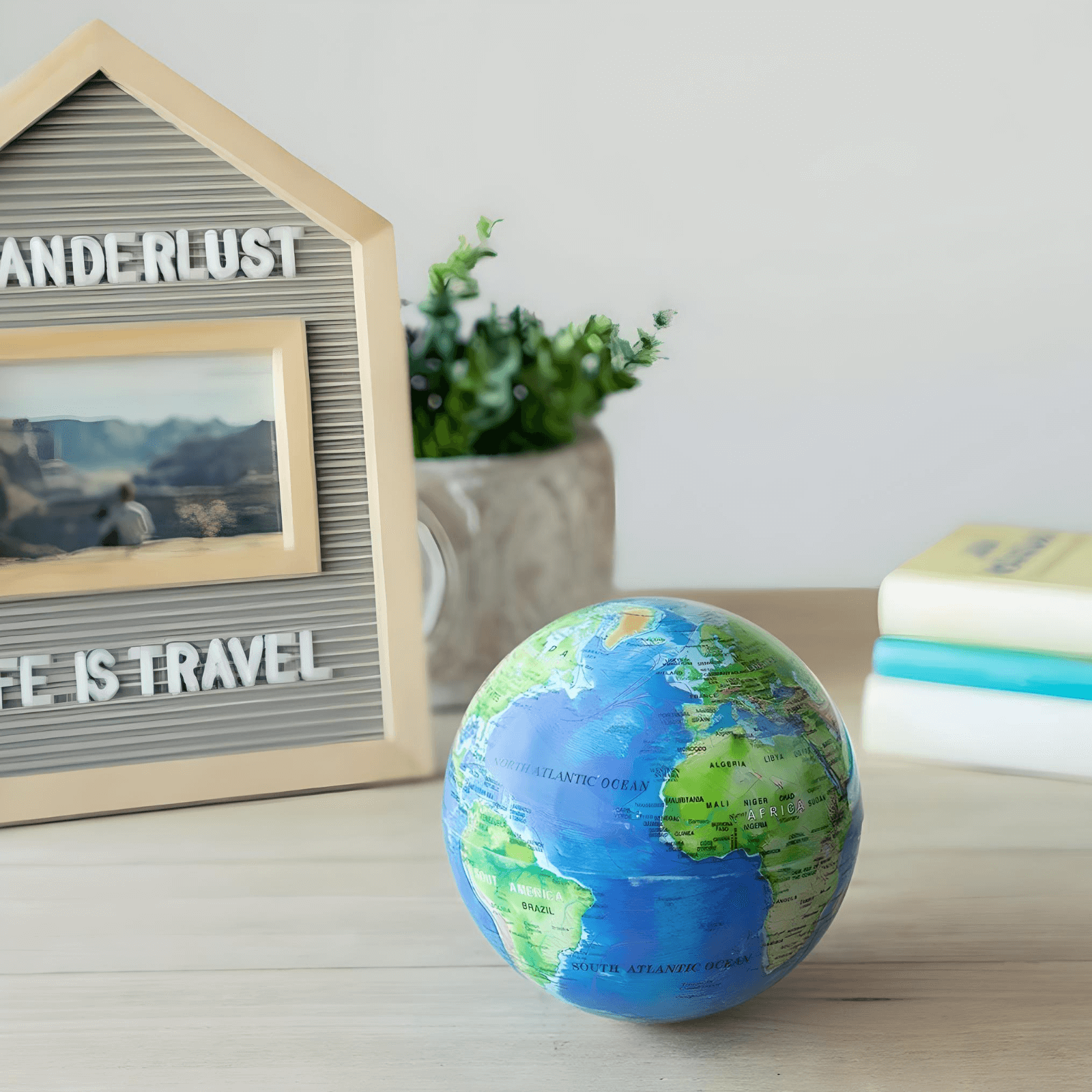 Balvi Magic Rotating Globe in blue, elegantly spinning on a desk with a decorative frame and books in the background.