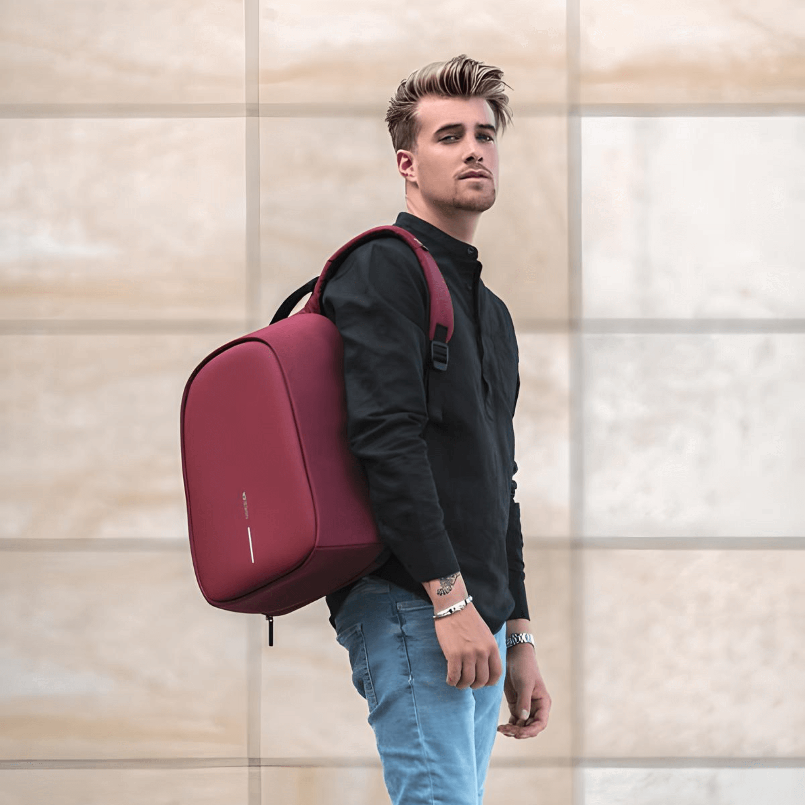 Stylish man wearing Bobby Hero Regular Anti-Theft Backpack in Cherry Red, showcasing modern design and security features.