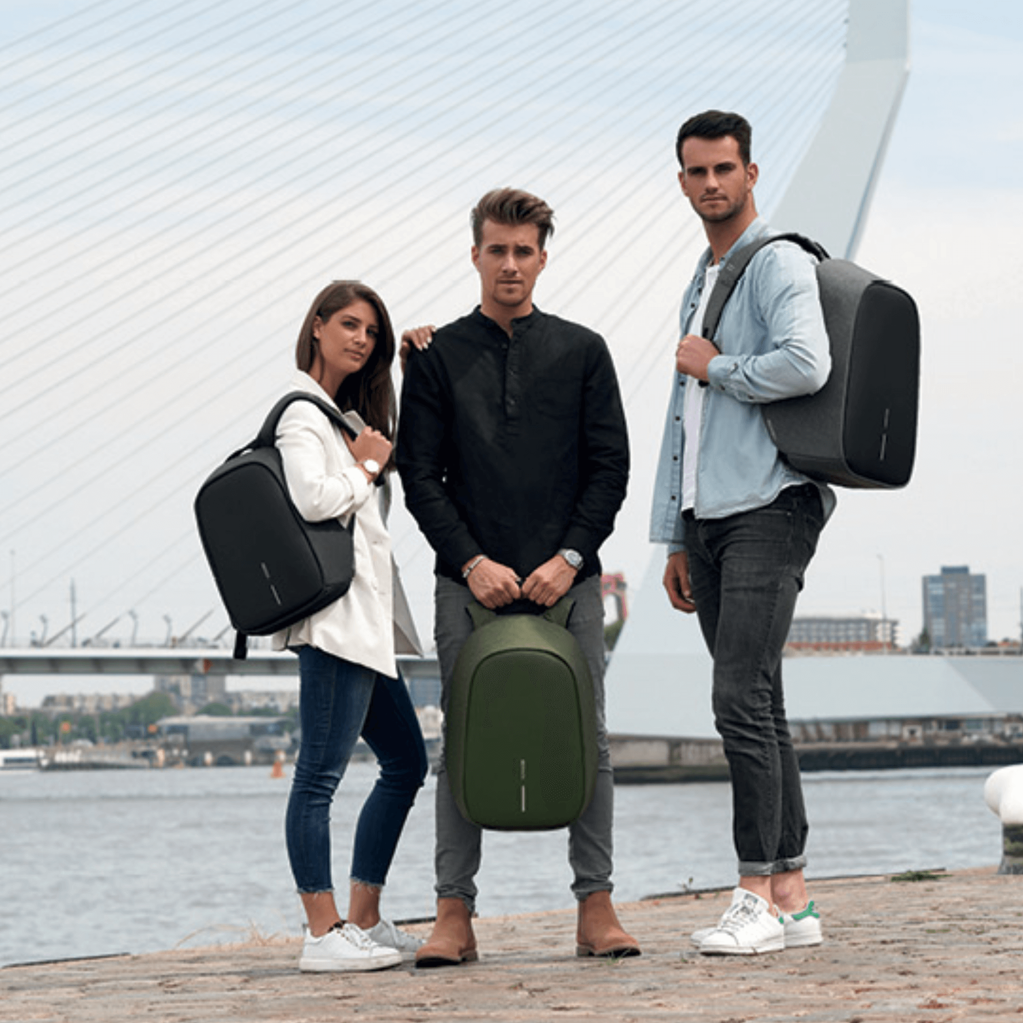 Three stylish individuals showcasing Bobby Hero backpacks in a waterfront setting, highlighting anti-theft design.