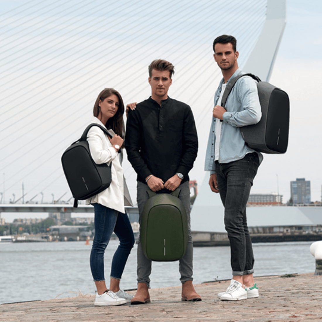 Three stylish individuals showcasing Bobby Hero backpacks in a waterfront setting, highlighting anti-theft design.