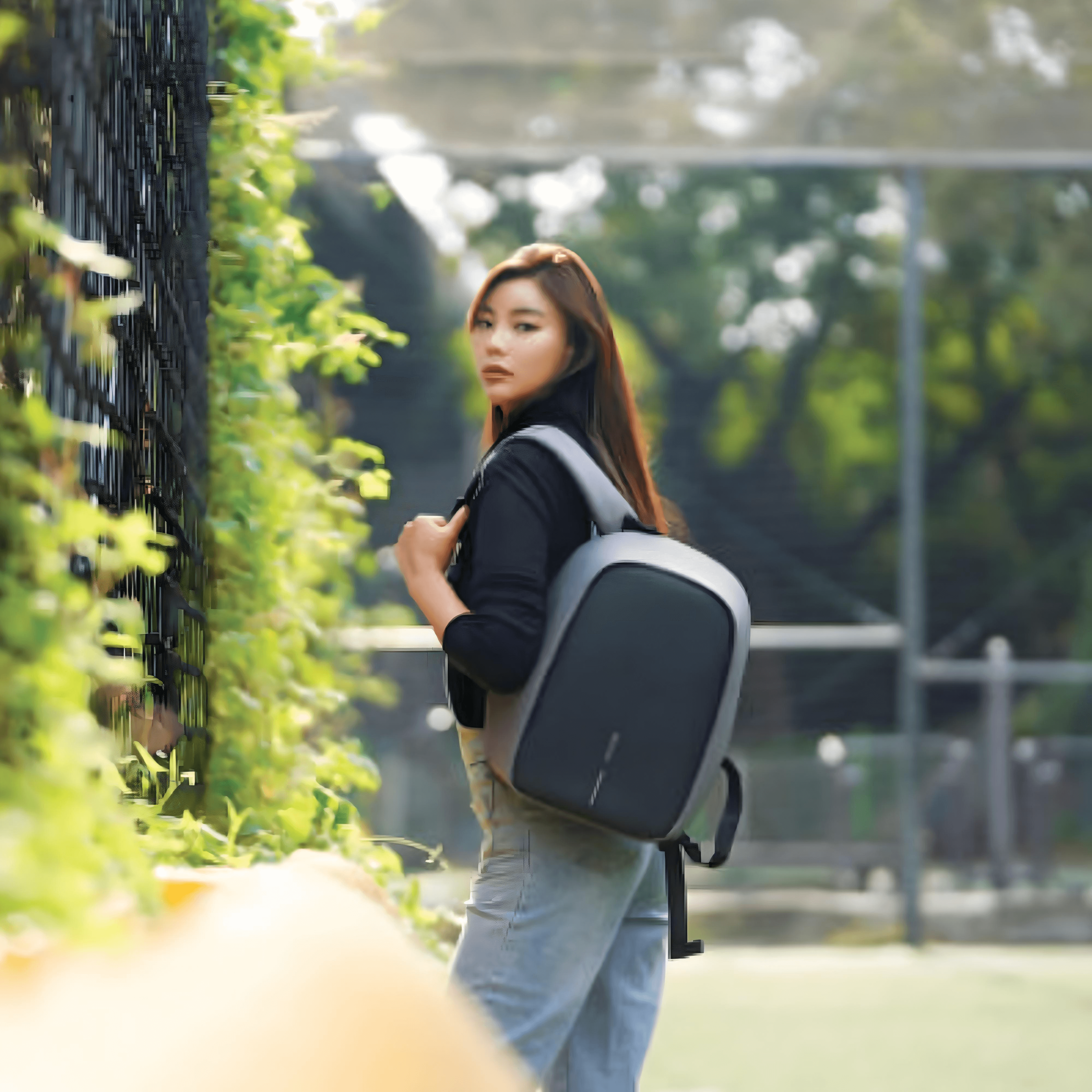 Woman with Bobby Hero Small Anti-theft Backpack in Grey, showcasing style and safety outdoors.