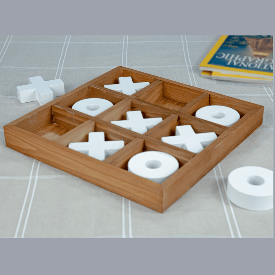 Deluxe Wooden Tic Tac Toe Game displayed on a table with white game pieces and a wooden tray.