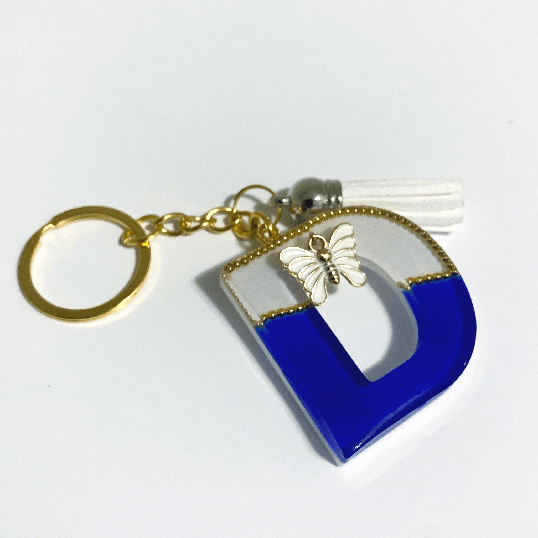 Keychain - Letter D with butterfly charm and tassel in white and blue tones, handcrafted UV resin design.