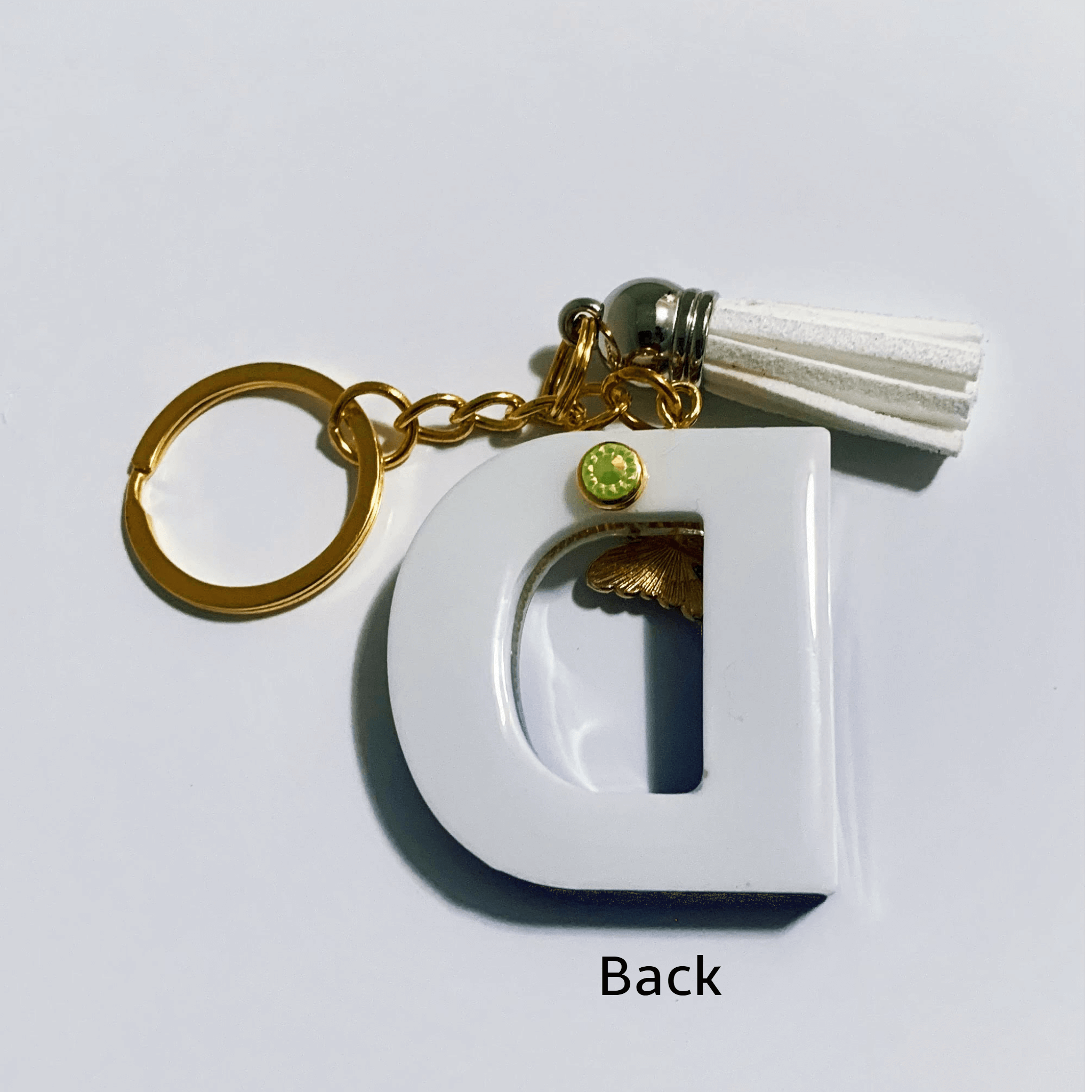Keychain - Letter D with gold tassel and marbled white design, showing the back view.