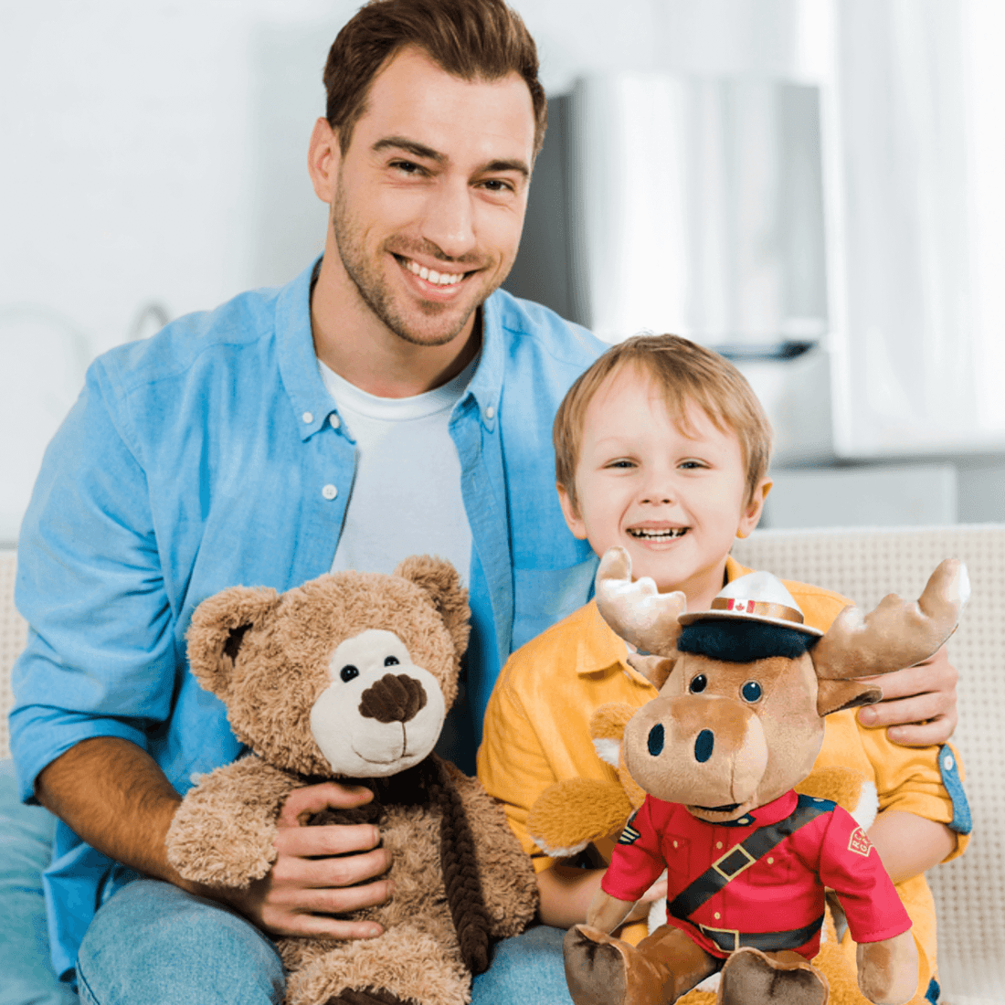 A father and son hold plush toys, including a RCMP Sergeant Moose, celebrating Canadian heritage.