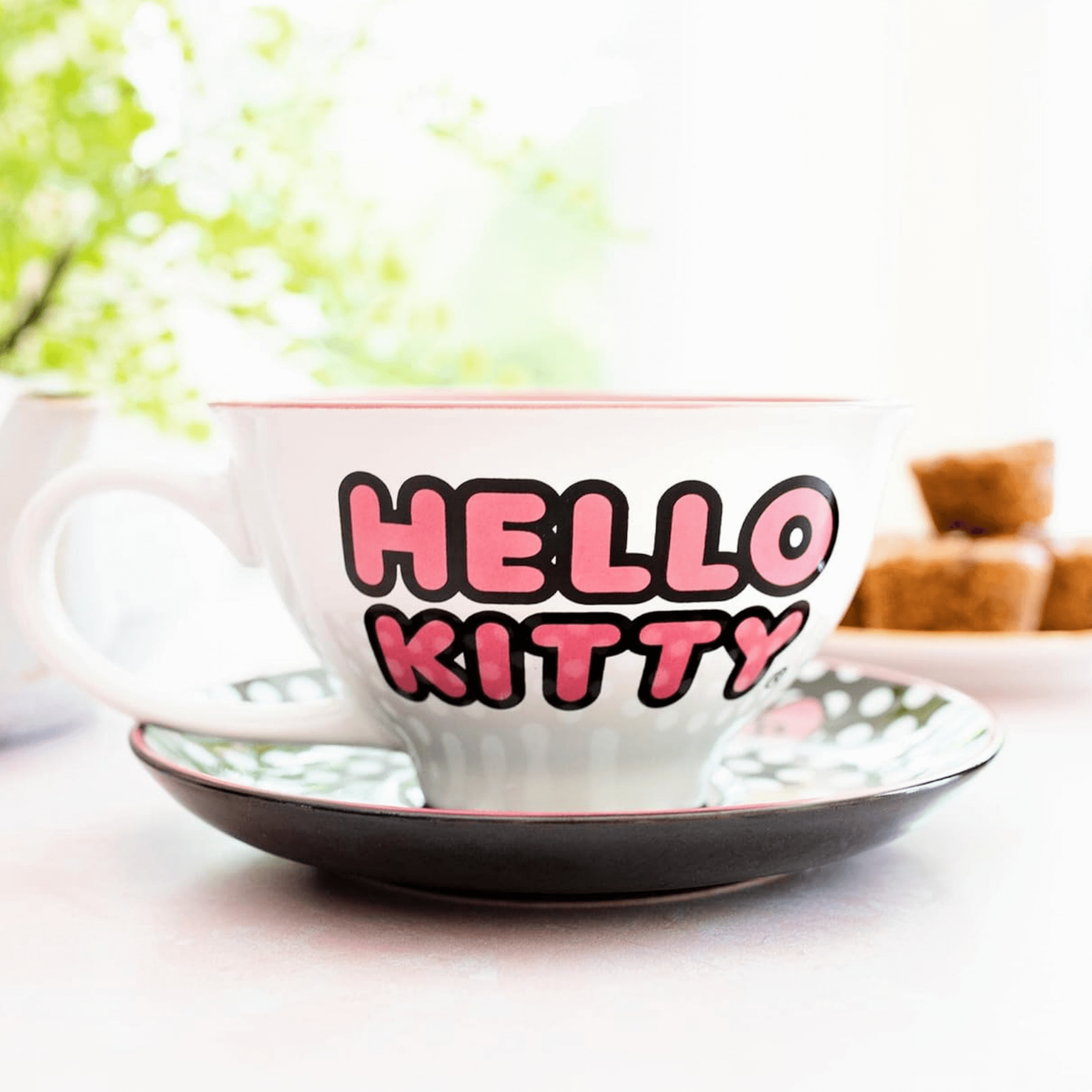 Hello Kitty teacup and saucer set featuring bold 'Hello Kitty' text, perfect for tea lovers and collectors.