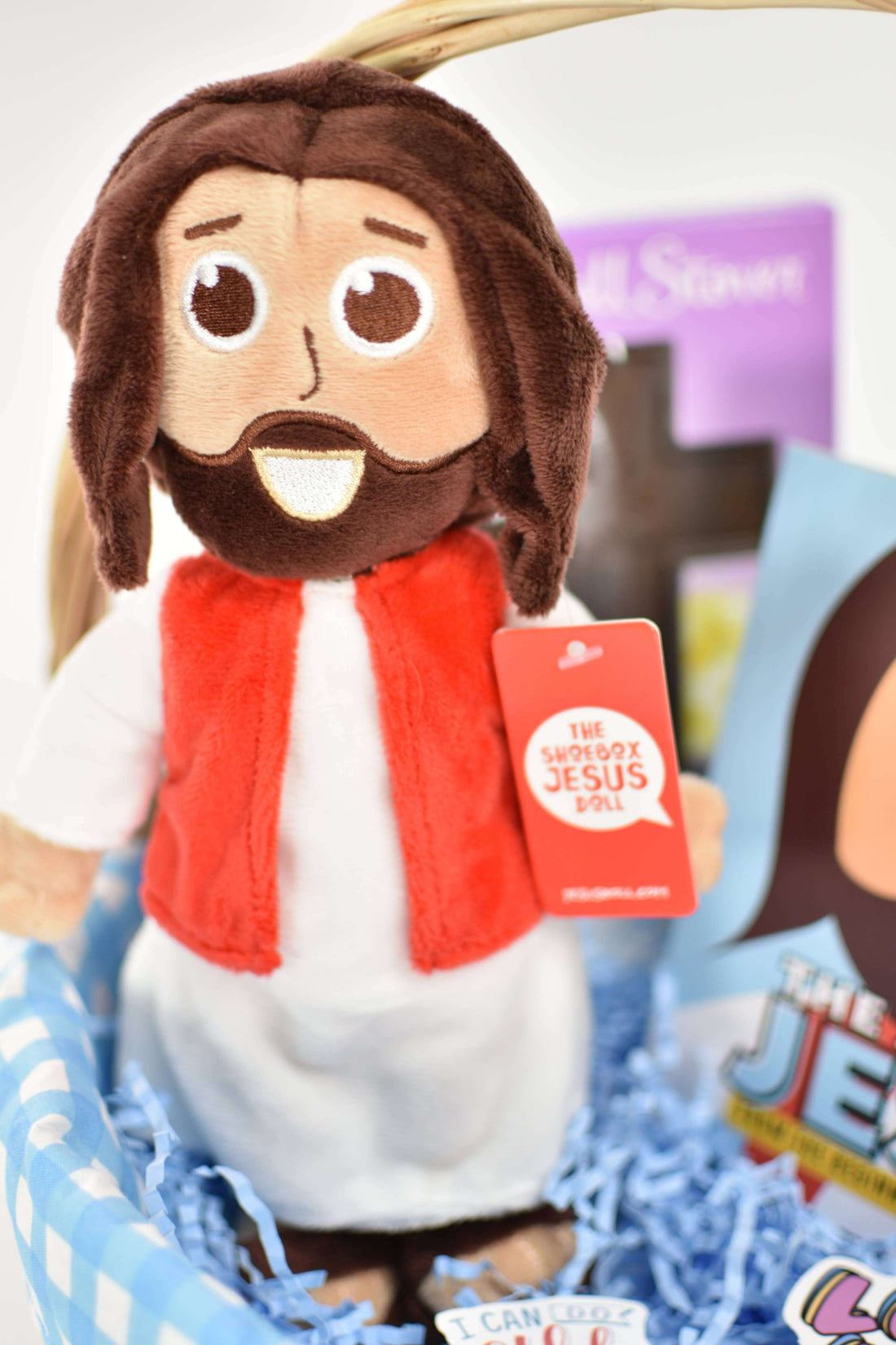 Plush Jesus doll in a basket with colorful books, perfect for kids' faith-based gifting.