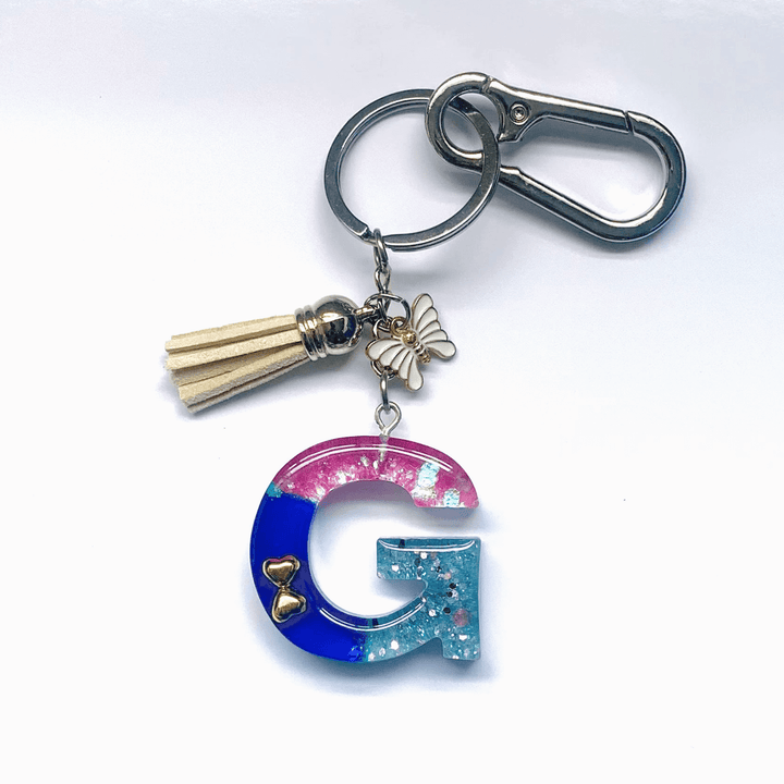 Letter G Keychain with Carabiner – Glitter & Tassel Charm featuring a colorful design and butterfly embellishment.