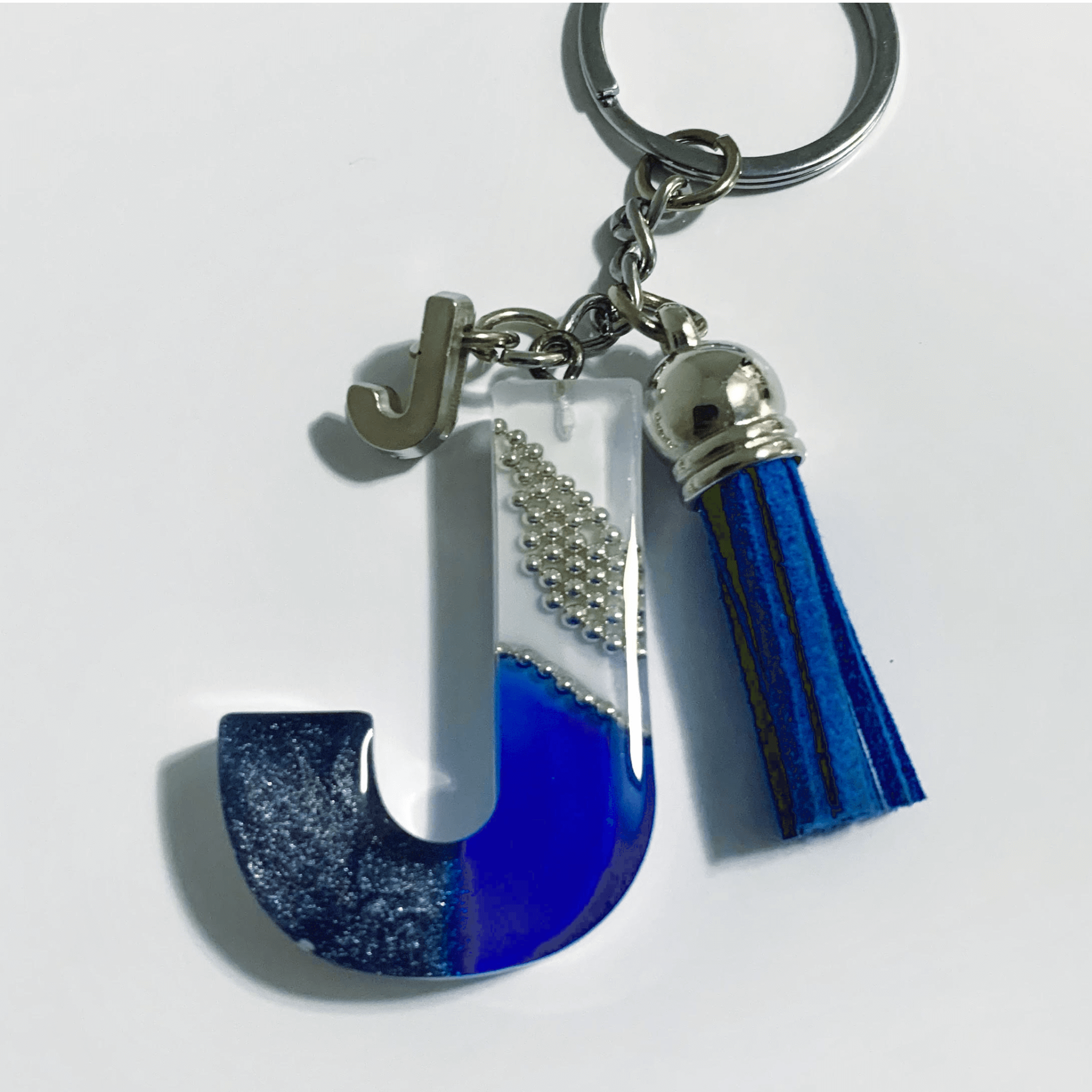 Letter J Resin Keychain – White & Blue Marbled Charm with tassel and metallic accents.