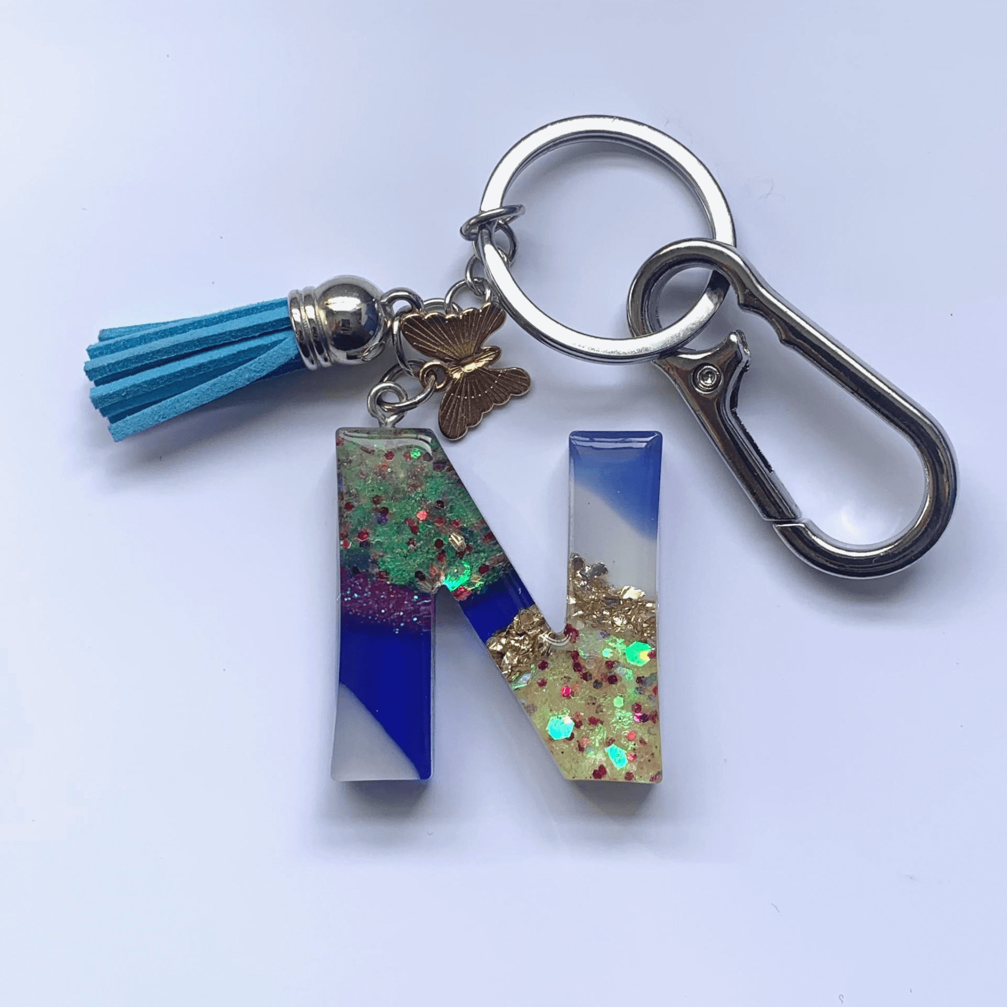 Letter N Keychain with Carabiner – Glitter & Tassel Charm featuring blue tassel and butterfly embellishment.