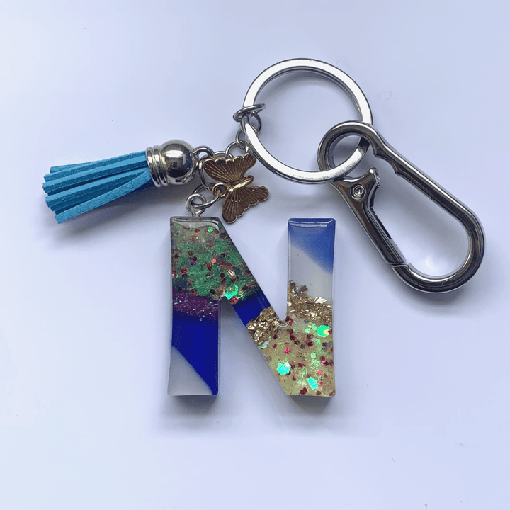 Letter N Keychain with Carabiner – Glitter & Tassel Charm featuring blue tassel and butterfly embellishment.