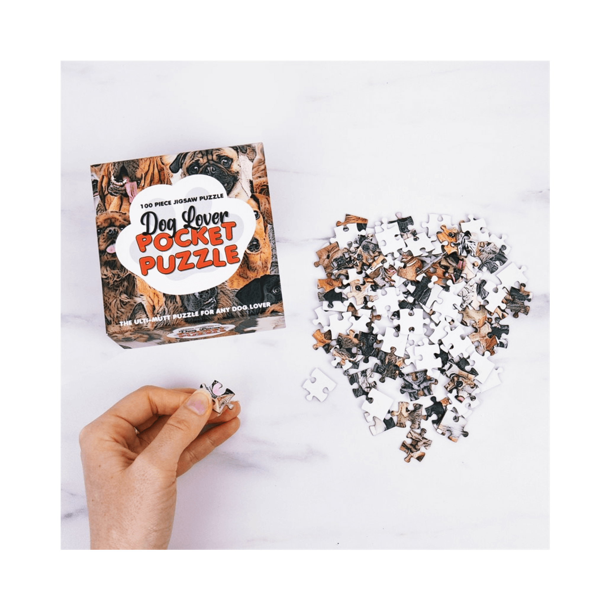 Pocket Puzzles for Dog Lovers - 100 piece puzzle laid out with a hand holding a piece.