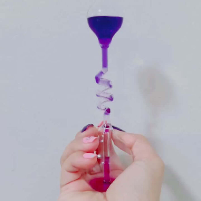 Hand boiler thermodynamics toy demonstrating liquid boiling with purple fluid in a glass chamber held by a hand.