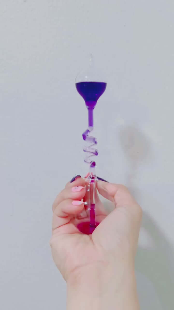 Hand boiler thermodynamics toy demonstrating liquid boiling with purple fluid in a glass chamber held by a hand.