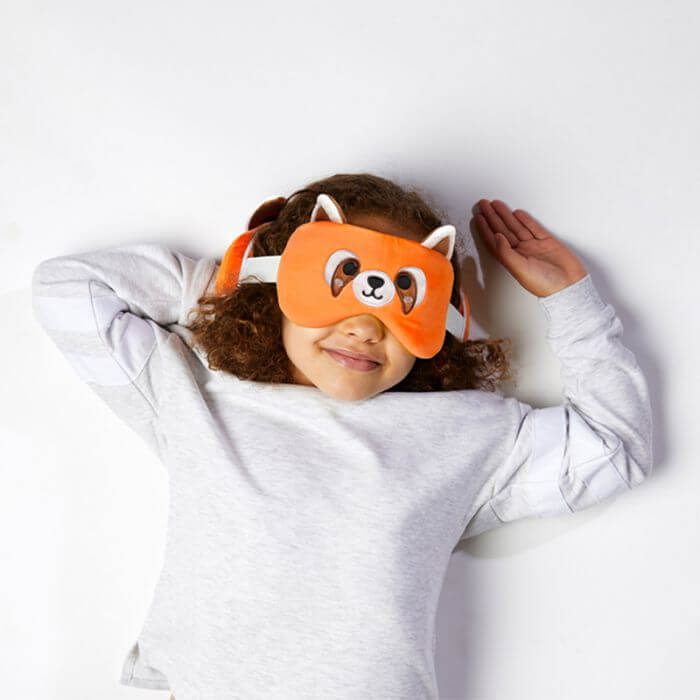 Girl wearing a fun Red Panda Travel Plush eye mask, relaxing and enjoying comfort while traveling.
