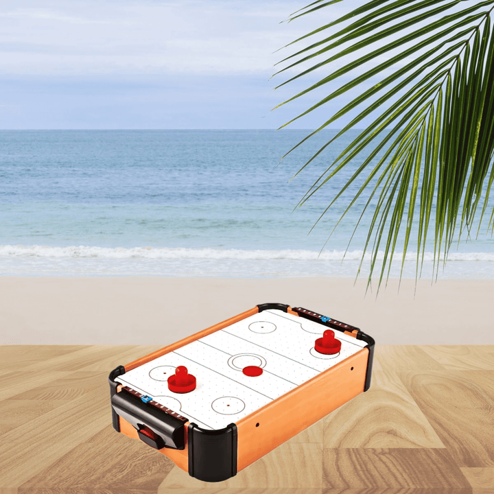 Tabletop Air Hockey Game with wooden frame, red paddles and puck displayed on a table with a beach background.