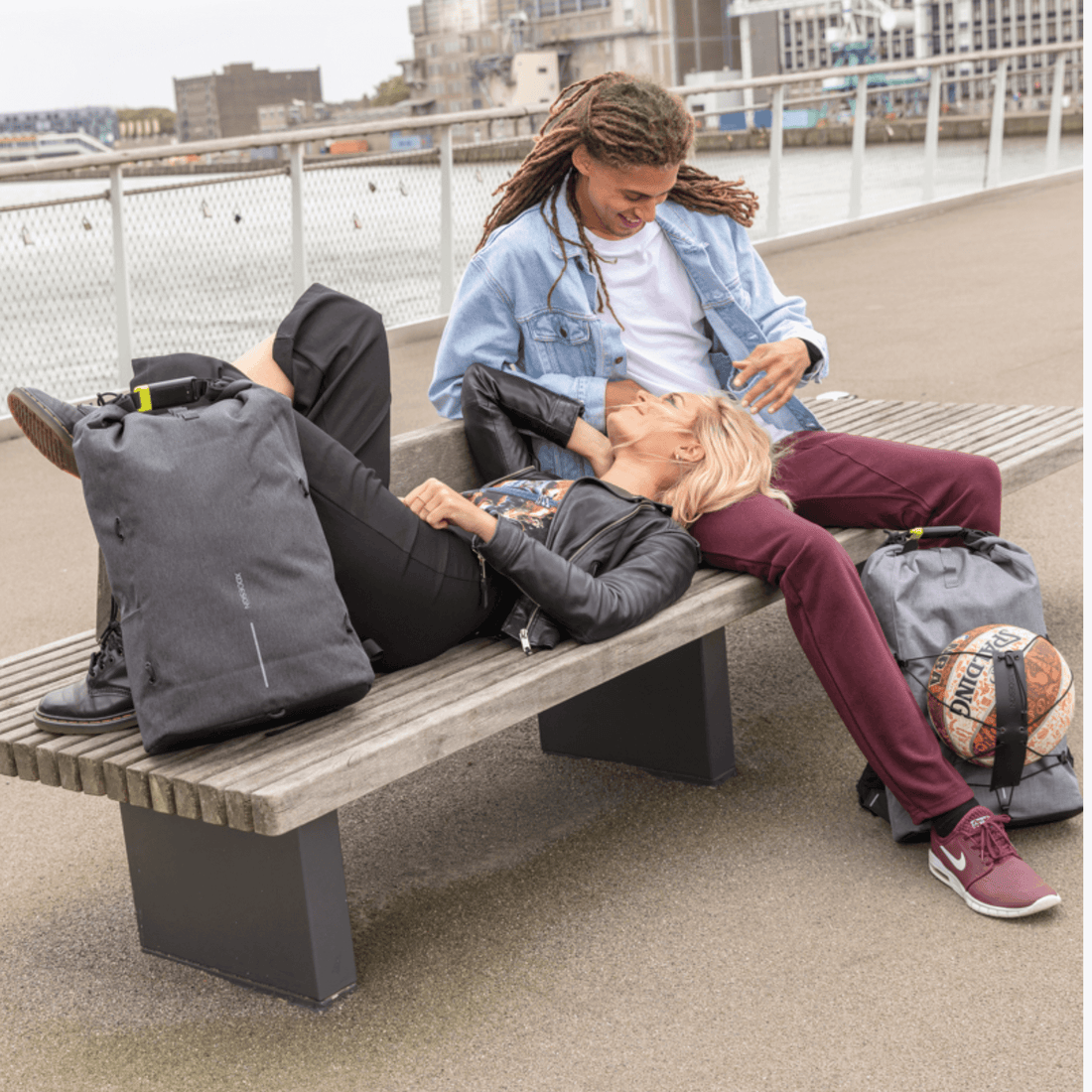 Couple enjoying time together on a bench with XD Design Bobby Urban Lite backpacks in urban setting.