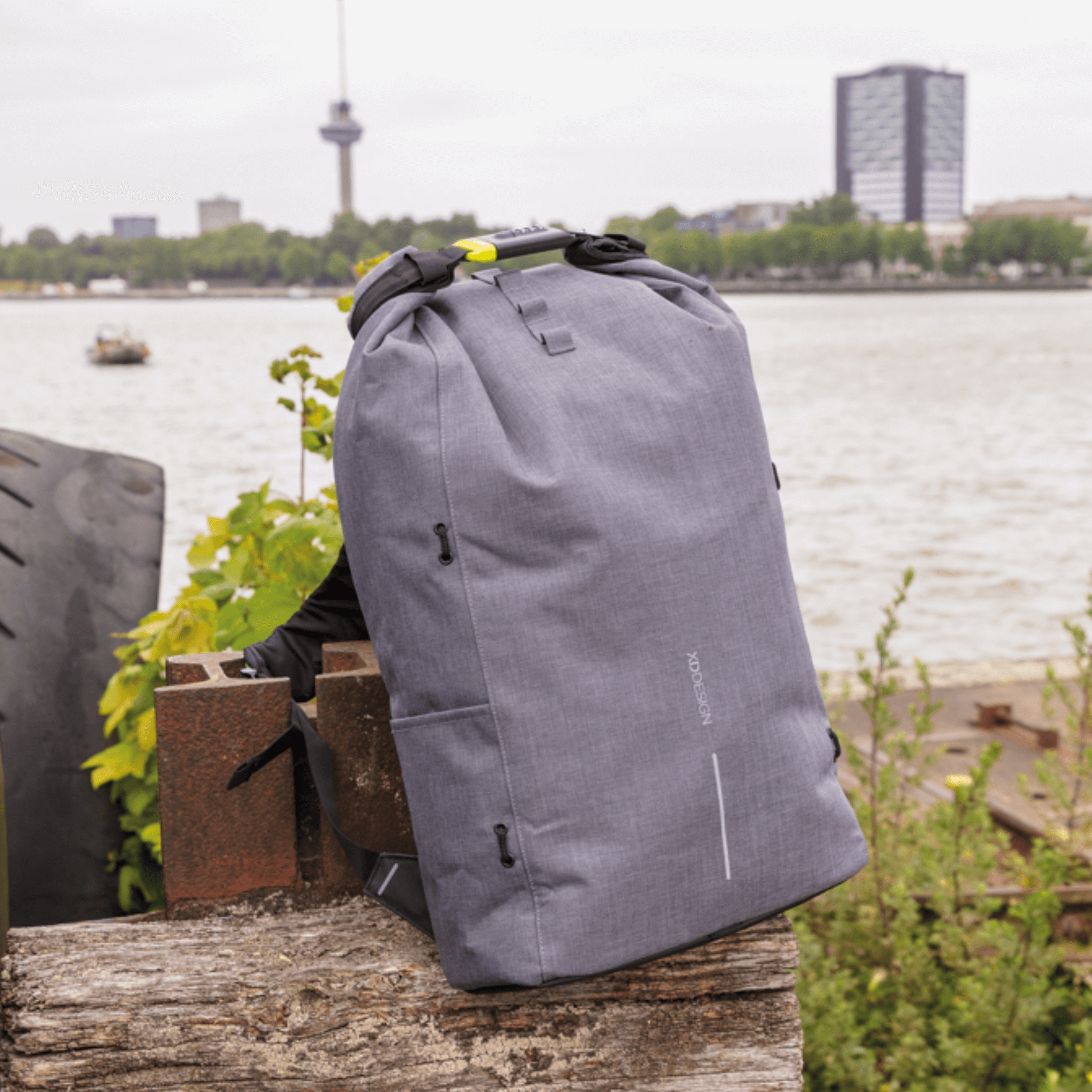 XD Design Bobby Urban Lite Anti Theft Laptop Backpack in grey by the river with city backdrop