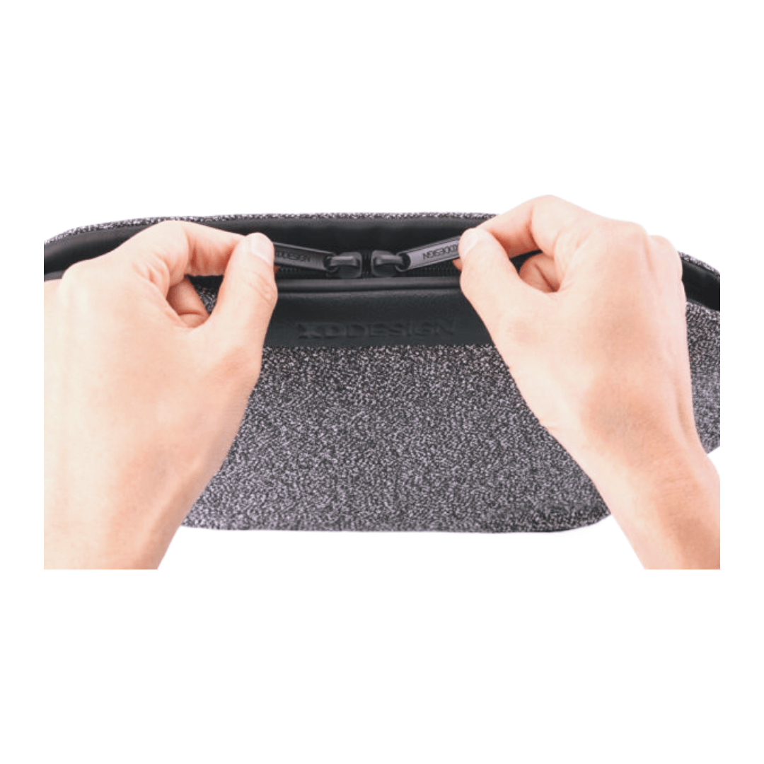 Hands holding the anti-theft zipper of the XD Design Urban Bumbag in grey.